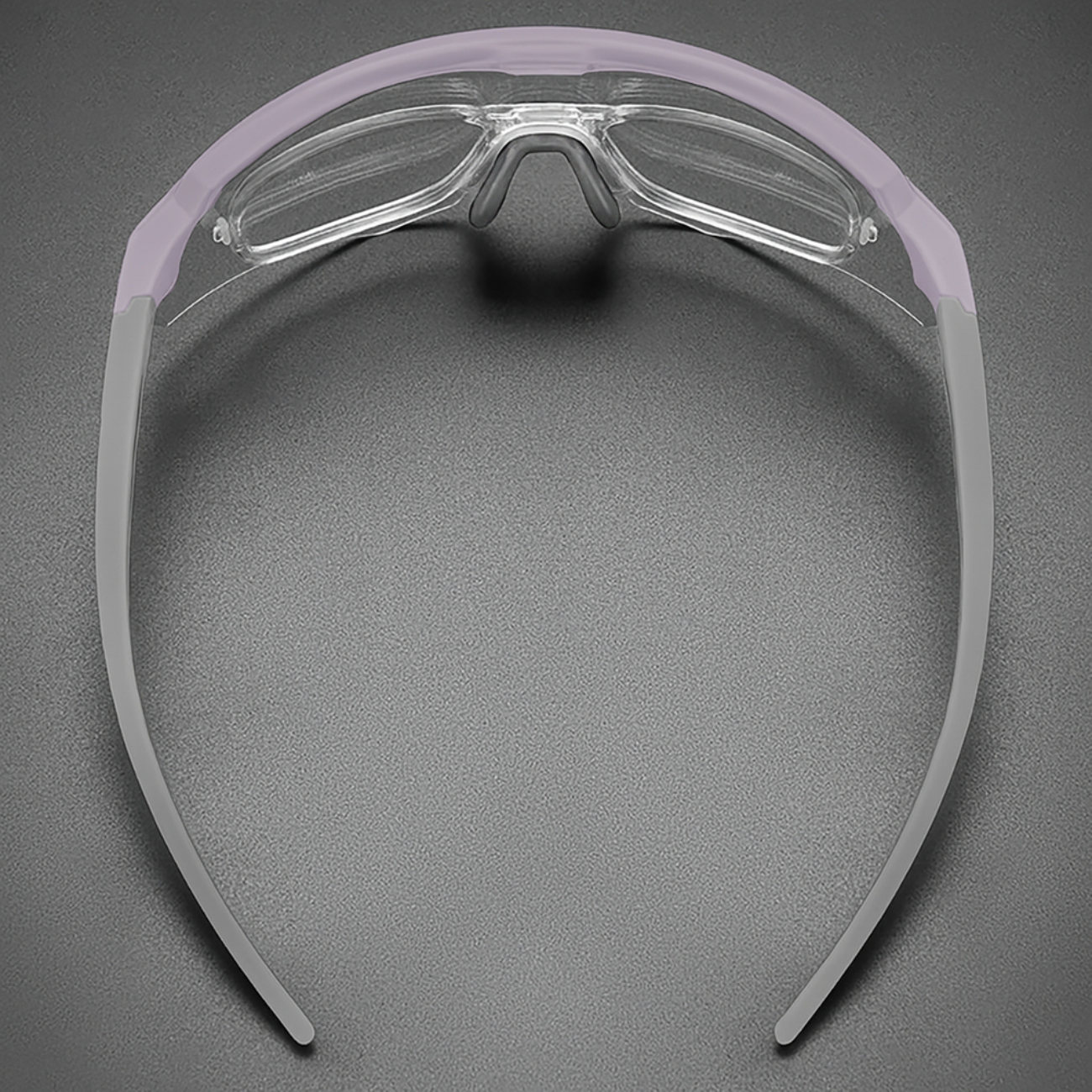 Nahaufnahme einer Schutzbrille mit klaren Gläsern und grauen Rahmen auf grauem Hintergrund.