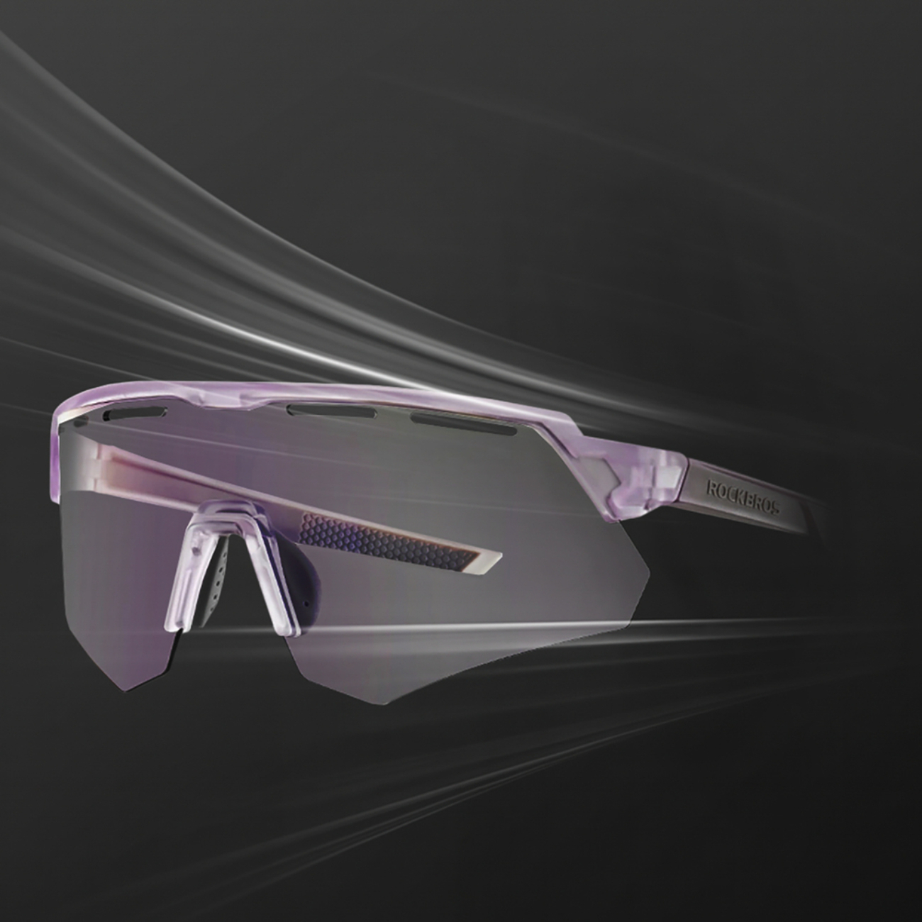 Violette Sportsonnenbrille mit klaren Gläsern und der Marke "ROCKBROS" am Bügel, vor dunklem Hintergrund mit Lichtstreifen.