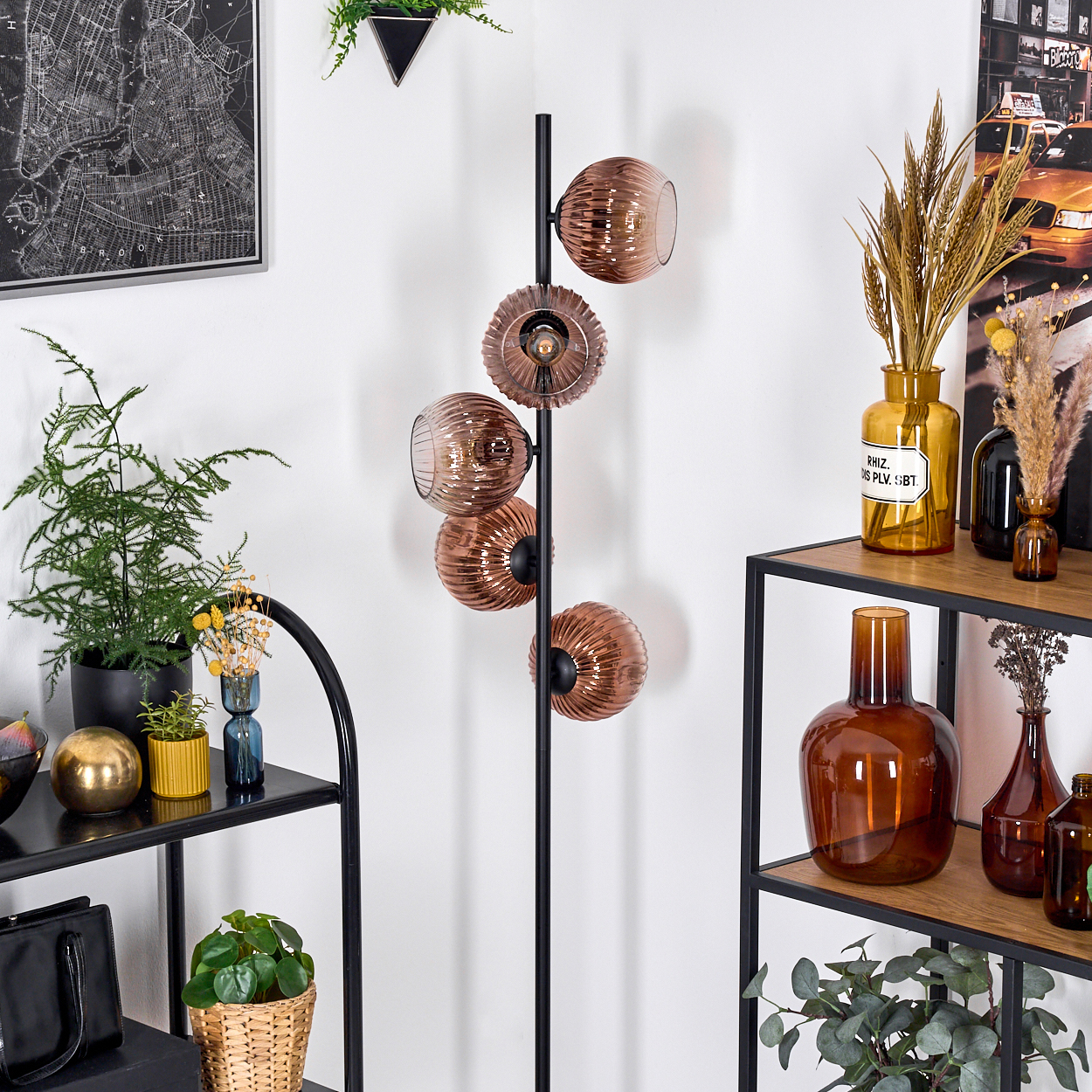 Moderne Inneneinrichtung mit schwarzer Lampe mit runden Glasschirmen. Regale mit Vasen und Pflanzen sind sichtbar. Eine Karte hängt an der Wand.