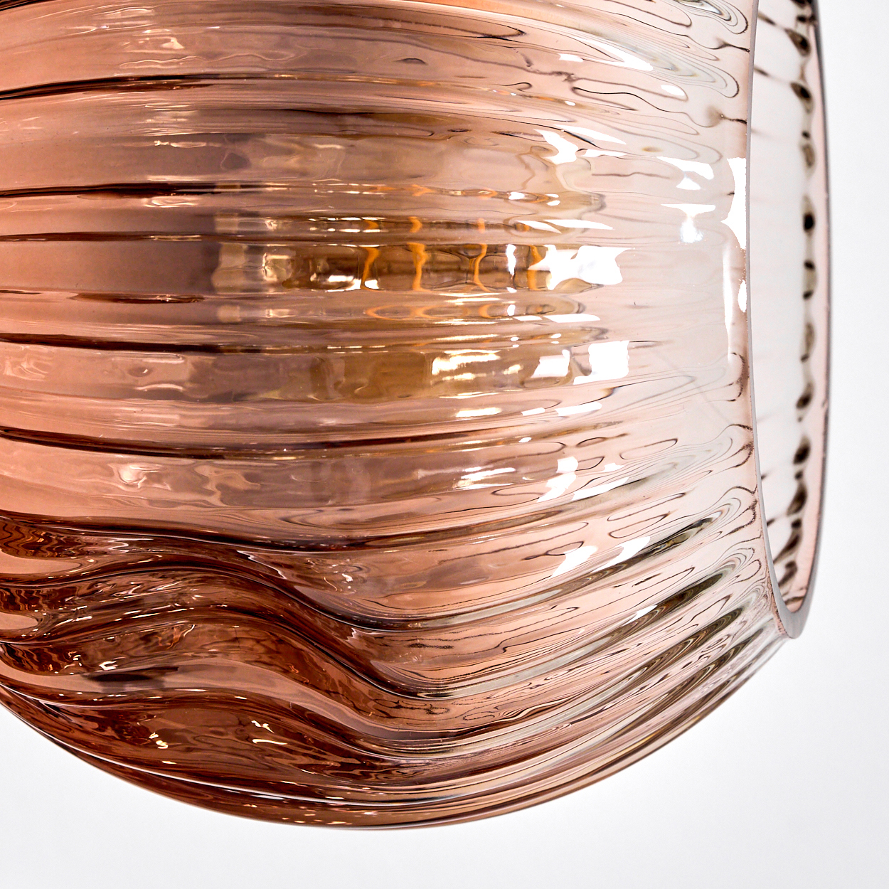 Nahaufnahme eines Glasobjekts mit horizontalen, wellenförmigen Linien. Das Glas ist hellrosa und reflektiert Licht.
