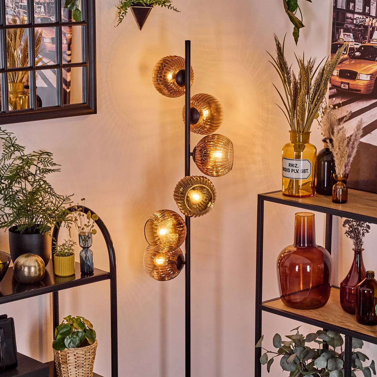 Ein modernes Wohnzimmer mit einer einzigartigen Lampe, Regalen, Pflanzen, Vasen und einem Bild.