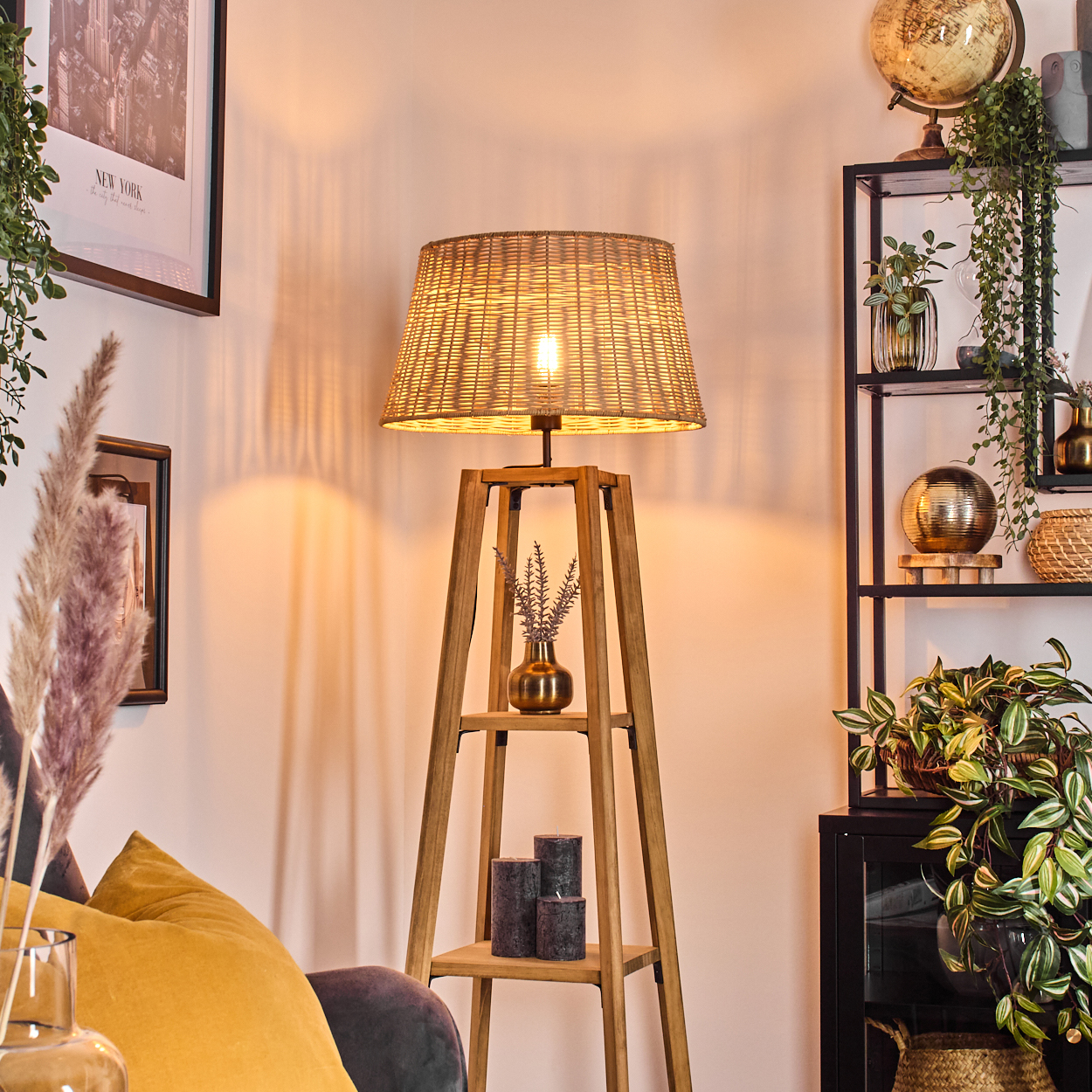 Ein Raum mit einer Holzlampe, Pflanzen, einem Regal, einem Globus und gerahmten Bildern. Die Lampe ist beleuchtet.