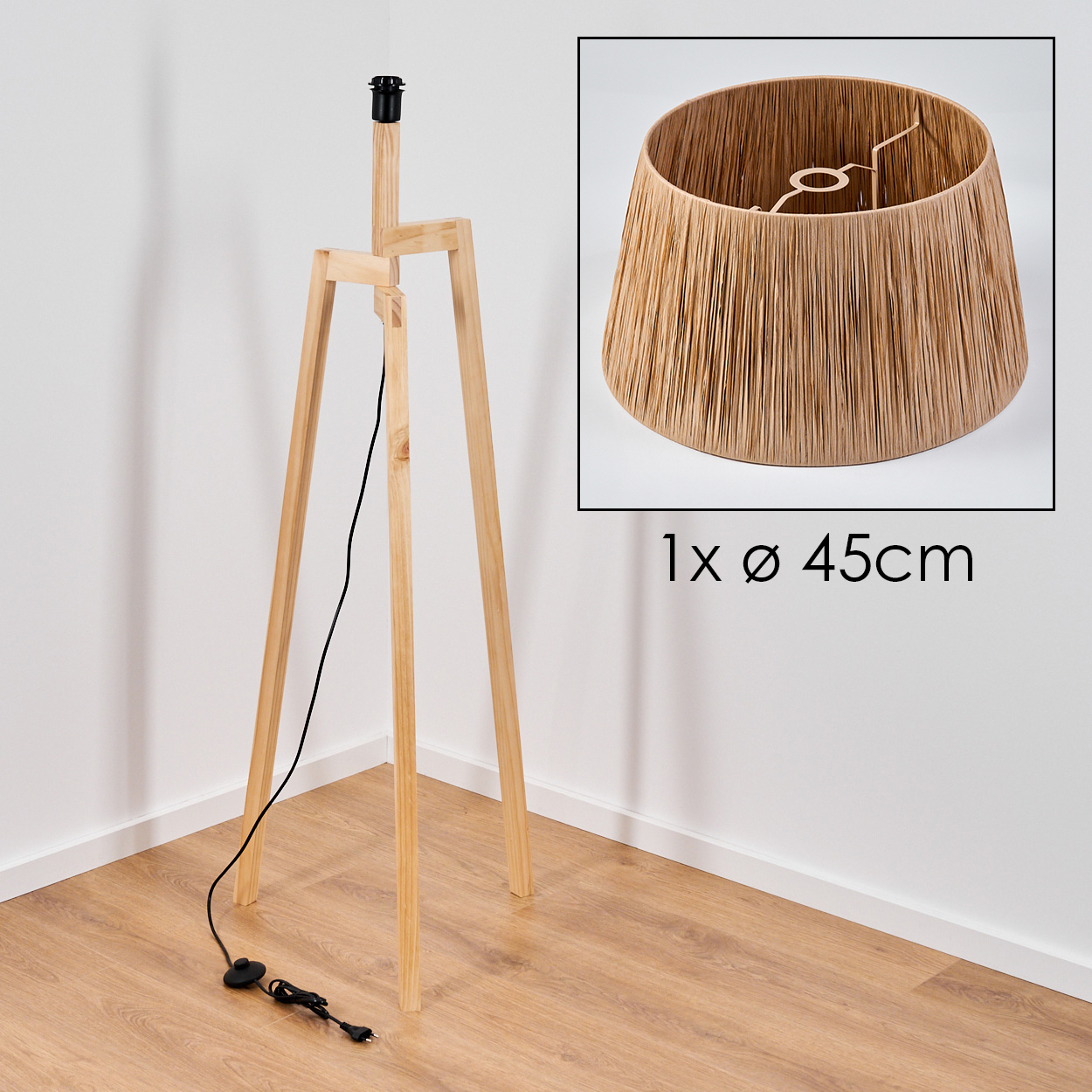 Holz-Stativ-Stehlampe mit beigem Lampenschirm. Die Lampe steht auf einem Holzboden, der Hintergrund ist eine weiße Wand.