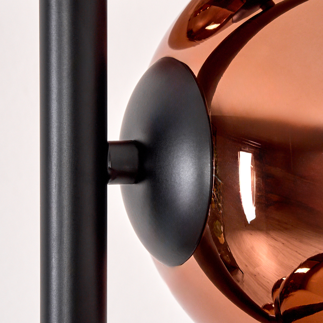 Nahaufnahme einer modernen Lampe. Eine schwarze Metallstange verbindet sich mit einer kupferfarbenen Kugel mit einer schwarzen Scheibe.