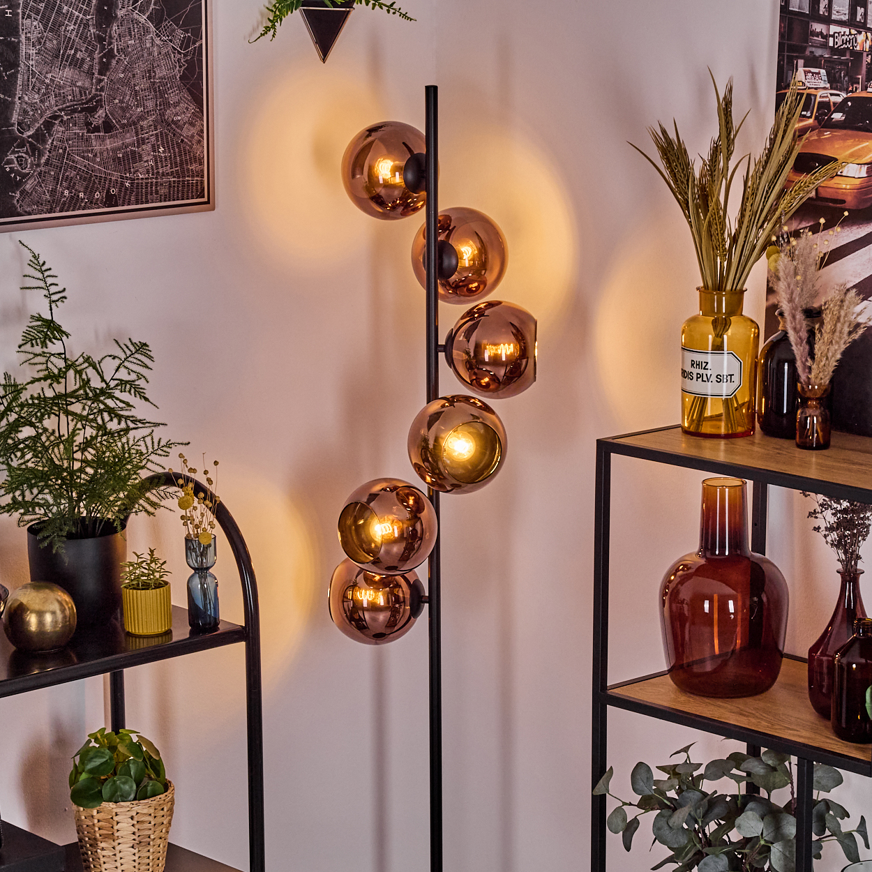 Ein modernes Zimmer mit Stehlampe mit Kupfersphären, Regalen mit Vasen, Pflanzen und einem Karten-Druck.