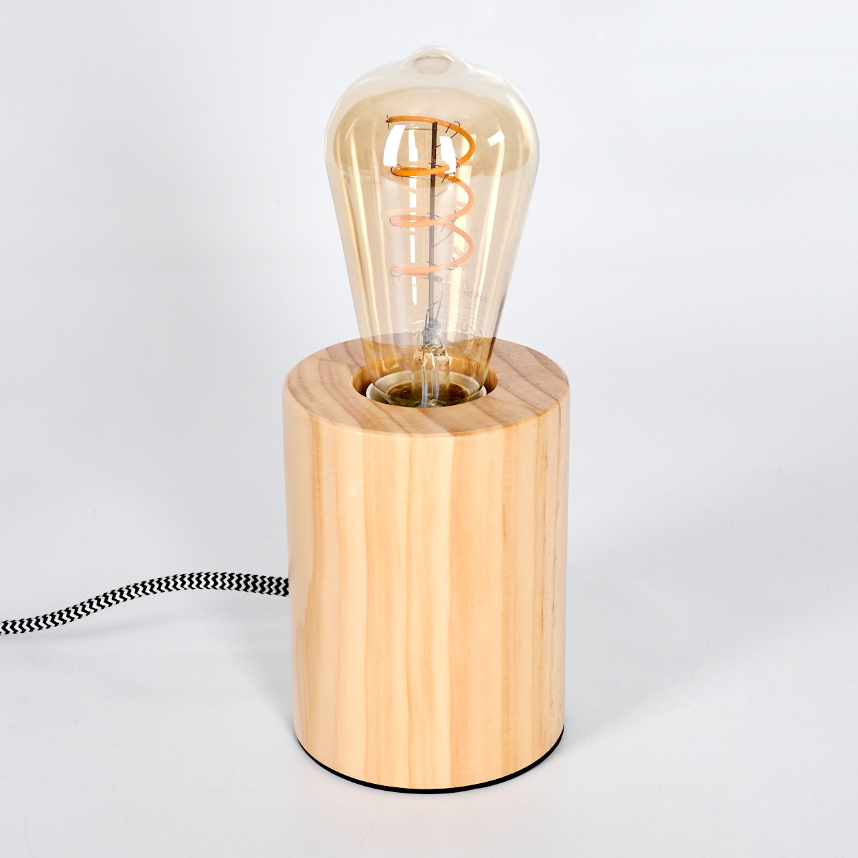 Eine Holzlampe mit einer großen Glühbirne im Vintage-Stil. Die Glühbirne ist bernsteinfarben, der Sockel zylindrisch.