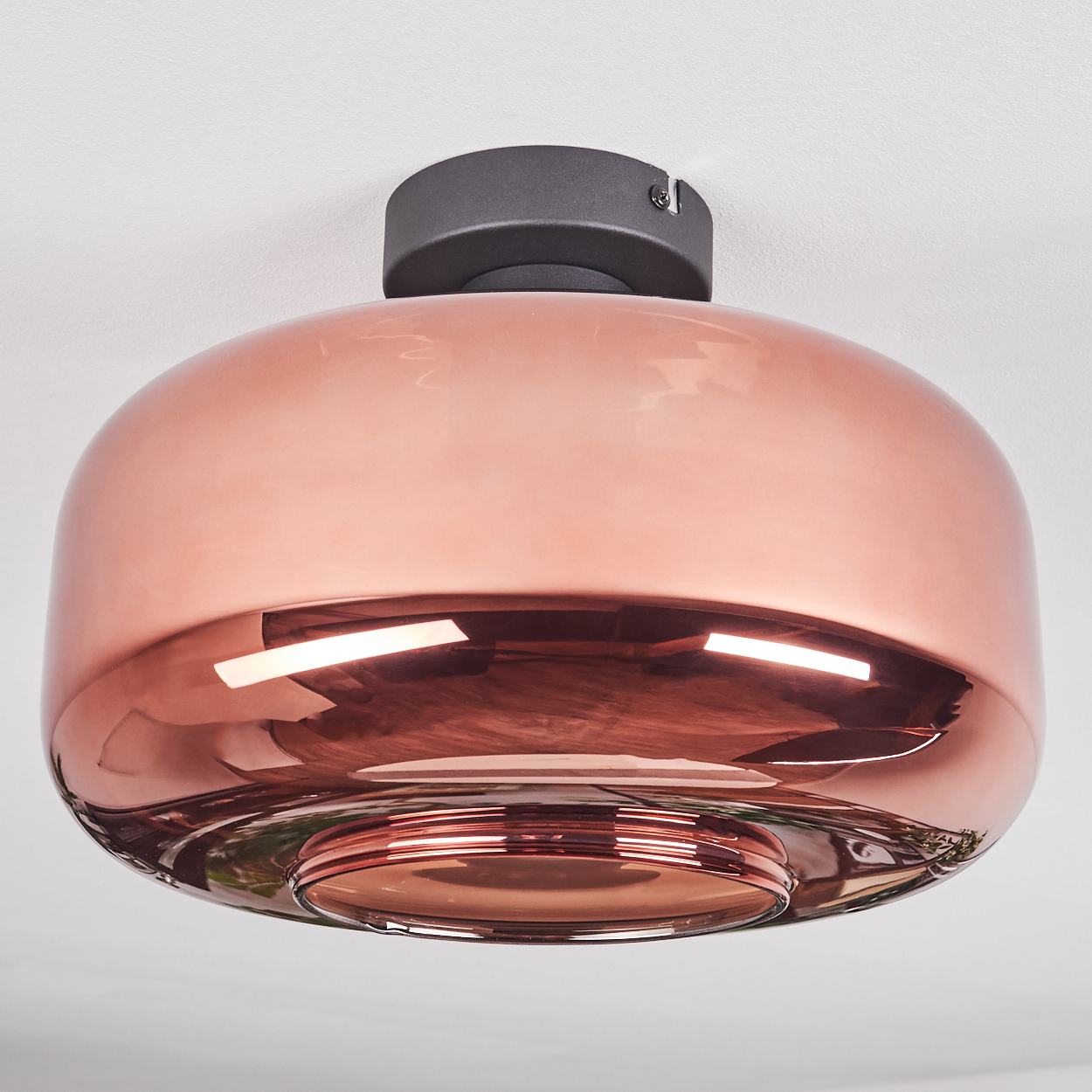 Eine moderne Deckenleuchte. Sie hat einen kupferfarbenen, abgerundeten Glasschirm, der an einer schwarzen Basis an der Decke befestigt ist.