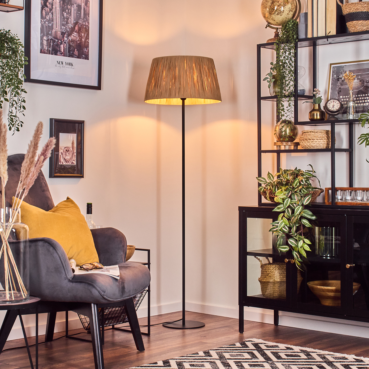 Wohnzimmerszene mit Stehlampe, Sessel und schwarzem Regal mit Pflanzen und Dekorationen.