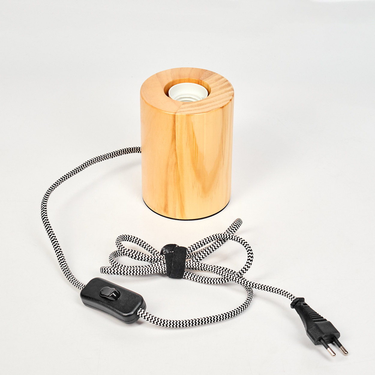 Eine zylindrische Holzlampe mit Lampenfassung. Sie hat ein schwarz-weißes Zickzack-Musterkabel, einen Schalter und einen Stecker.