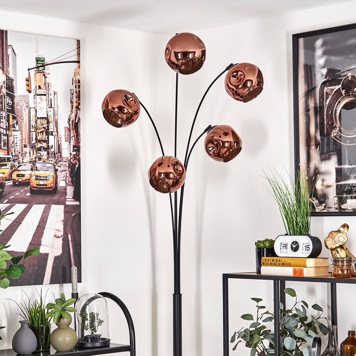 Ein modernes Wohnzimmer mit einer Kupferlampe. Ein New York City-Bild hängt an der Wand, und dekorative Gegenstände stehen auf Regalen.