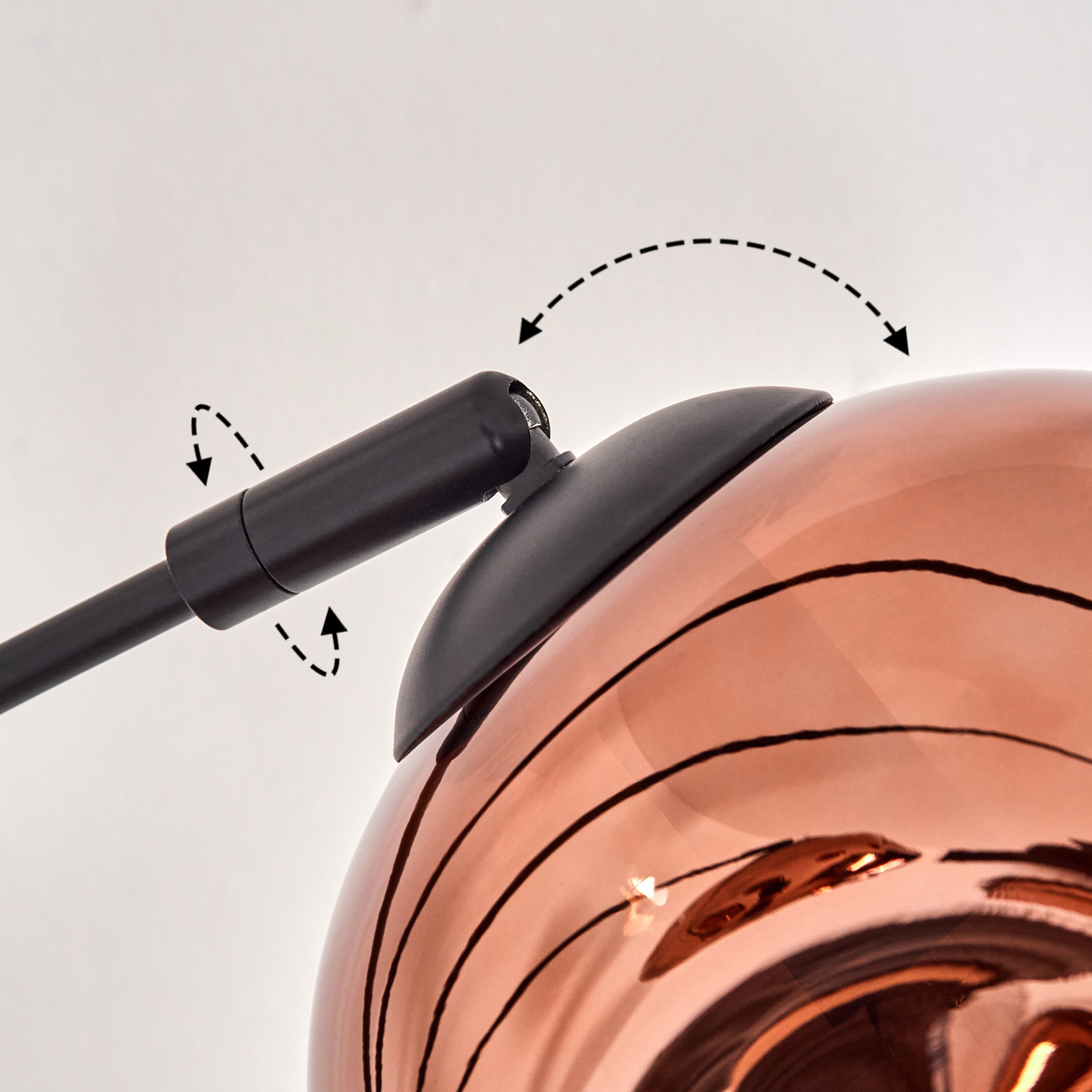 Nahaufnahme einer Kupferlampe mit schwarzem Arm. Der Arm ist an der Kupfersphäre befestigt. Der Hintergrund ist schlicht weiß.