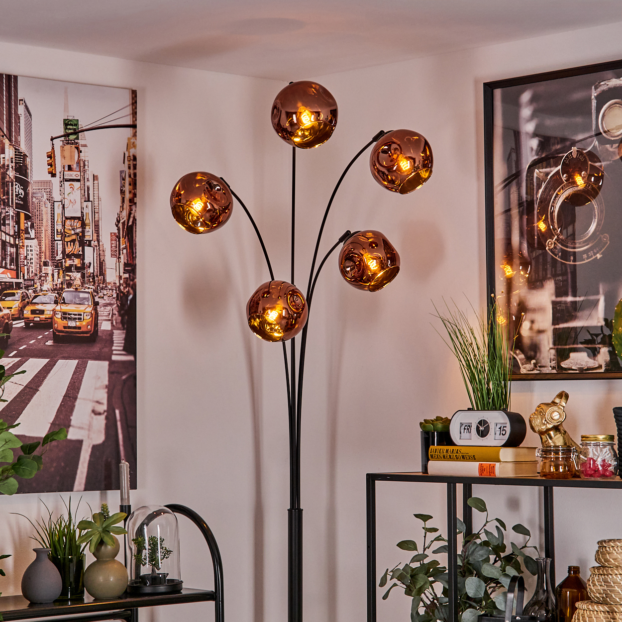 Ein modernes Wohnzimmer mit einer einzigartigen Lampe mit kupferfarbenen Kugeln. Ein New York City Bild hängt an der Wand, mit Deko auf einem Regal.