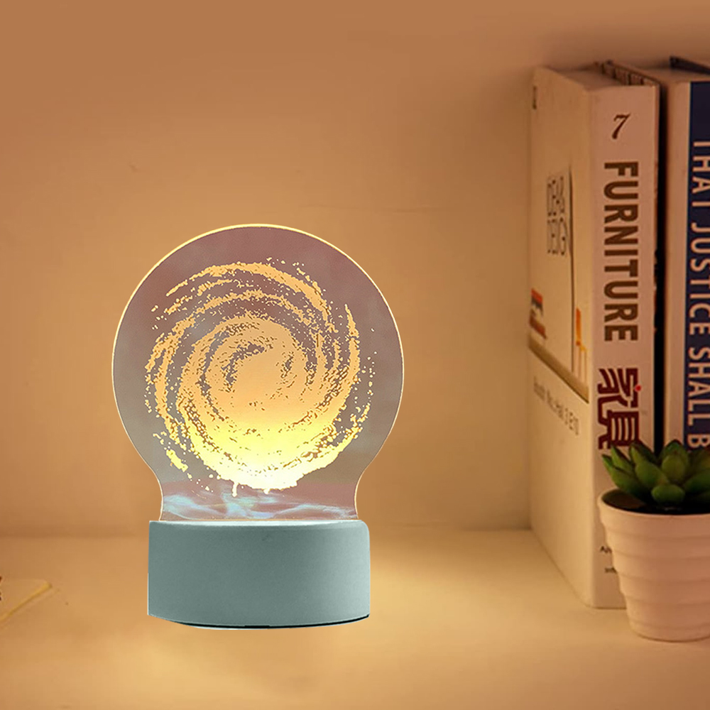 Eine galaxieförmige Lampe steht auf einem Regal. Bücher und eine kleine Topfpflanze sind im Hintergrund zu sehen.