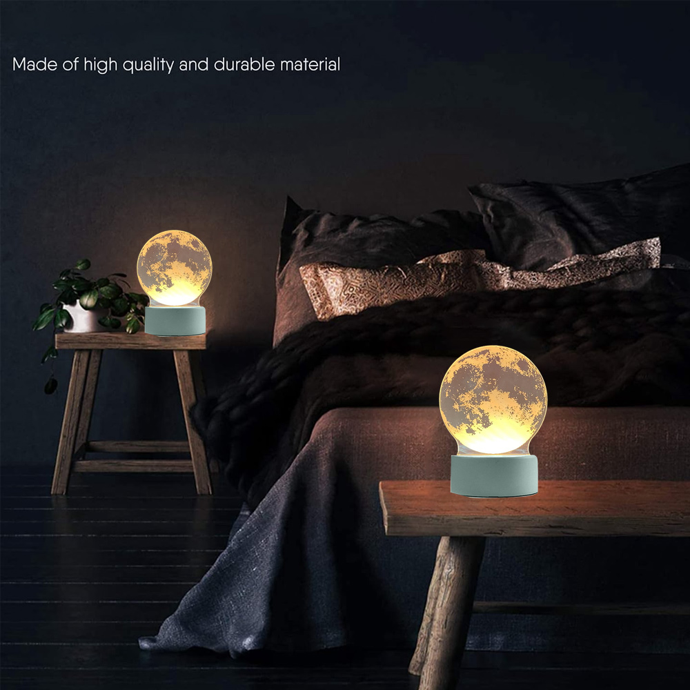 Zwei mondförmige Lampen auf Holztischen neben einem Bett. Die Lampen leuchten. Eine Pflanze steht neben einer.