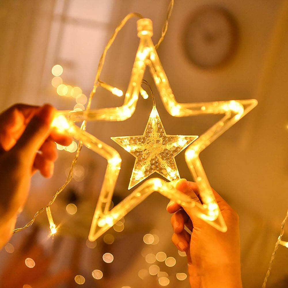 Hände halten ein leuchtendes sternförmiges Licht. Der Stern hat einen kleineren Stern im Inneren mit warmen, gelben Lichtern.