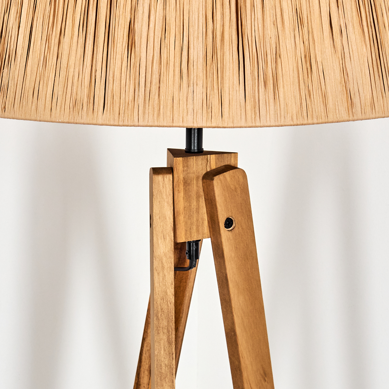 Nahaufnahme einer Holz-Stativlampe mit beigem Schirm. Die Lampe hat eine natürliche Holzoberfläche und einen weißen Hintergrund.