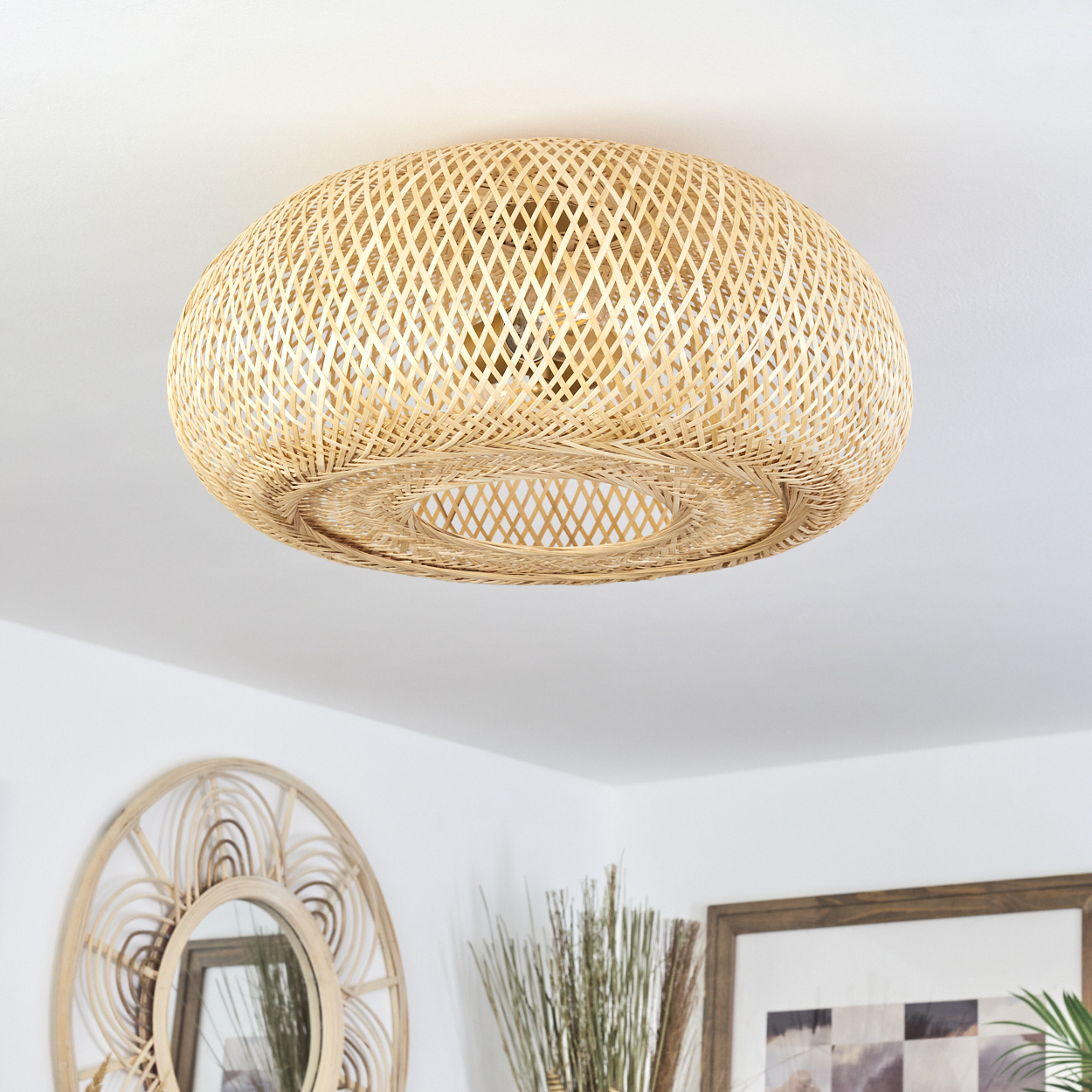 Eine gewebte Deckenlampe aus Rattan hängt. Ein Spiegel und gerahmte Kunstwerke befinden sich darunter. Die Lampe ist der Hauptfokus.