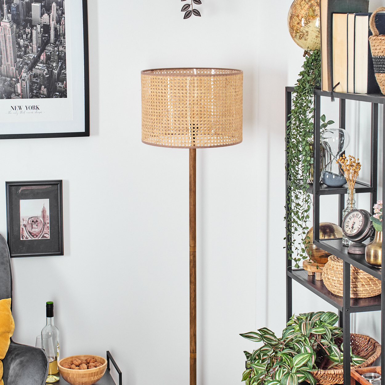 Ein Raum mit einer Lampe, einem Regal mit Dekorationen und gerahmten Bildern. Eine Schale mit Walnüssen und eine Weinflasche stehen auf einem Tisch.