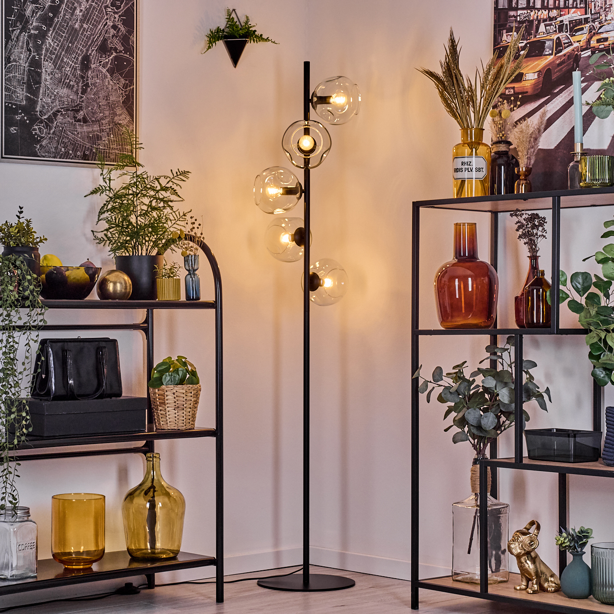 Raumecke mit Regalen, Pflanzen und einer Stehlampe mit kugelförmigen Lichtern. Verschiedene Vasen und Dekorationsartikel stehen auf den Regalen.