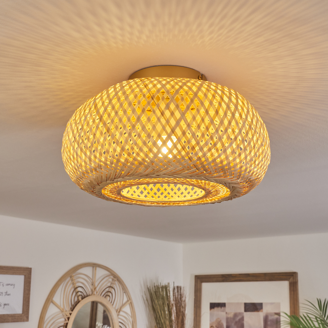 Eine Deckenlampe aus geflochtenem Bambus beleuchtet einen Raum. Licht scheint von der Lampe herab, und die Decke wirft Schatten.