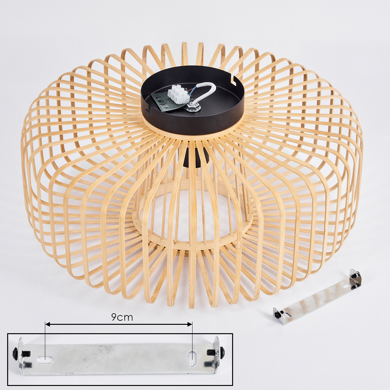 Ein gewebter Bambus-Lampenschirm mit schwarzem Oberteil. Eine Metallhalterung und elektrische Komponenten sind ebenfalls vorhanden. Die Szene befindet sich auf einer weißen Oberfläche.