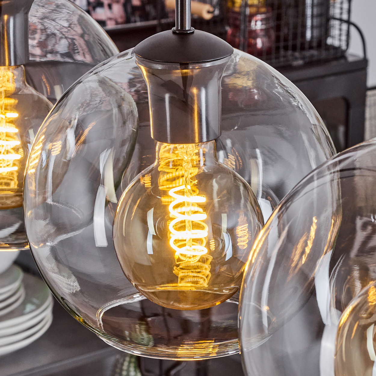 Nahaufnahme einer modernen Leuchte mit mehreren klaren Glaskugeln und Edison-Glühbirnen, die warm leuchten.