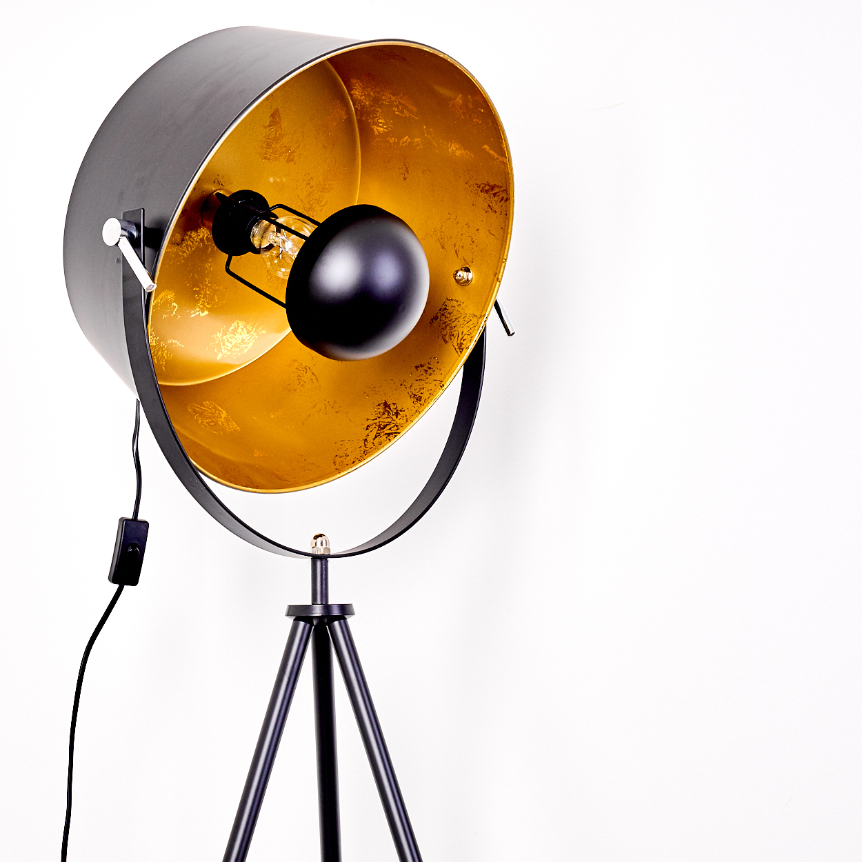 Eine moderne schwarze Stehlampe mit goldfarbenem Innenraum, die auf einem Dreibein steht. Der Hintergrund ist weiß.