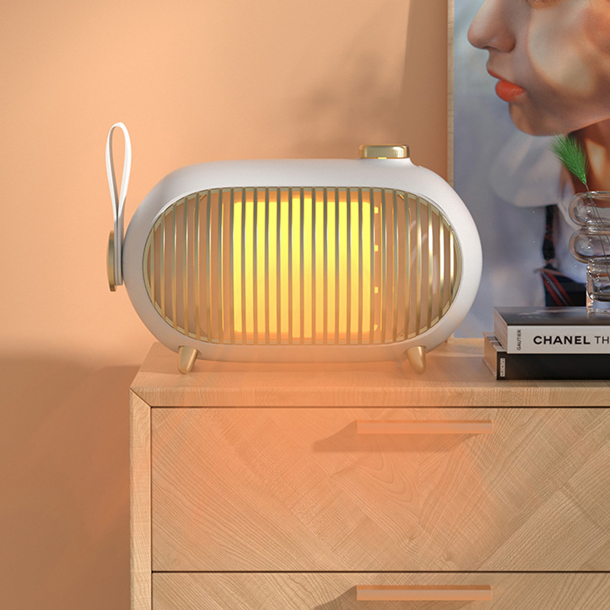 Eine weiße und goldene ovale Lampe auf einem Nachttisch aus Holz. Ein Gemälde und Bücher sind im Hintergrund.