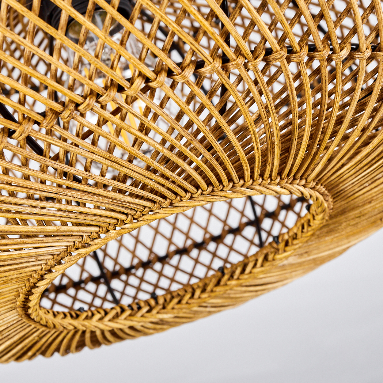 Nahaufnahme eines gewebten Rattan-Lampenschirms. Der Schirm ist hellbraun mit einer ovalen Öffnung. Der Hintergrund ist weiß.