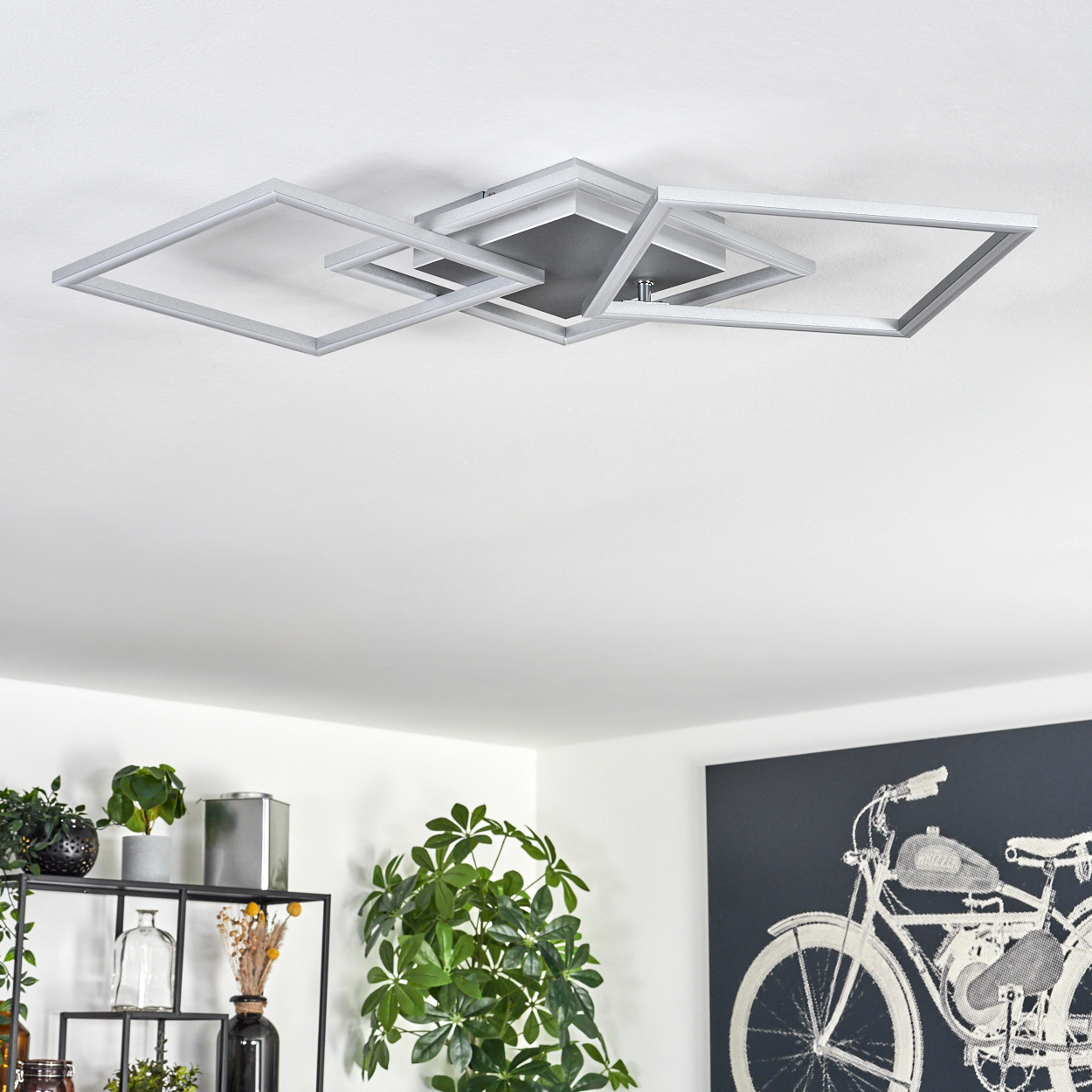 Moderne Deckenleuchte mit überlappenden quadratischen Rahmen. Darunter sind Pflanzen und ein Fahrradkunstwerk zu sehen.