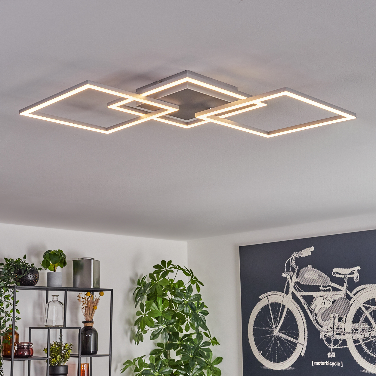 Moderne Deckenleuchte mit quadratischem Design. Pflanzen und ein Fahrradkunstwerk sind im Raum sichtbar.