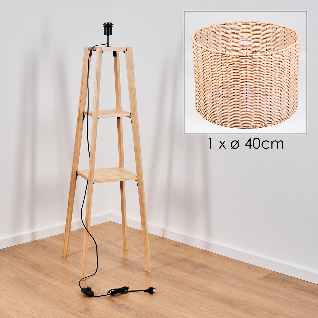 Holzlampe mit zwei Regalen, schwarzem Kabel und Rattanschirm. Die Lampe steht auf einem Holzboden, nahe einer weißen Wand.