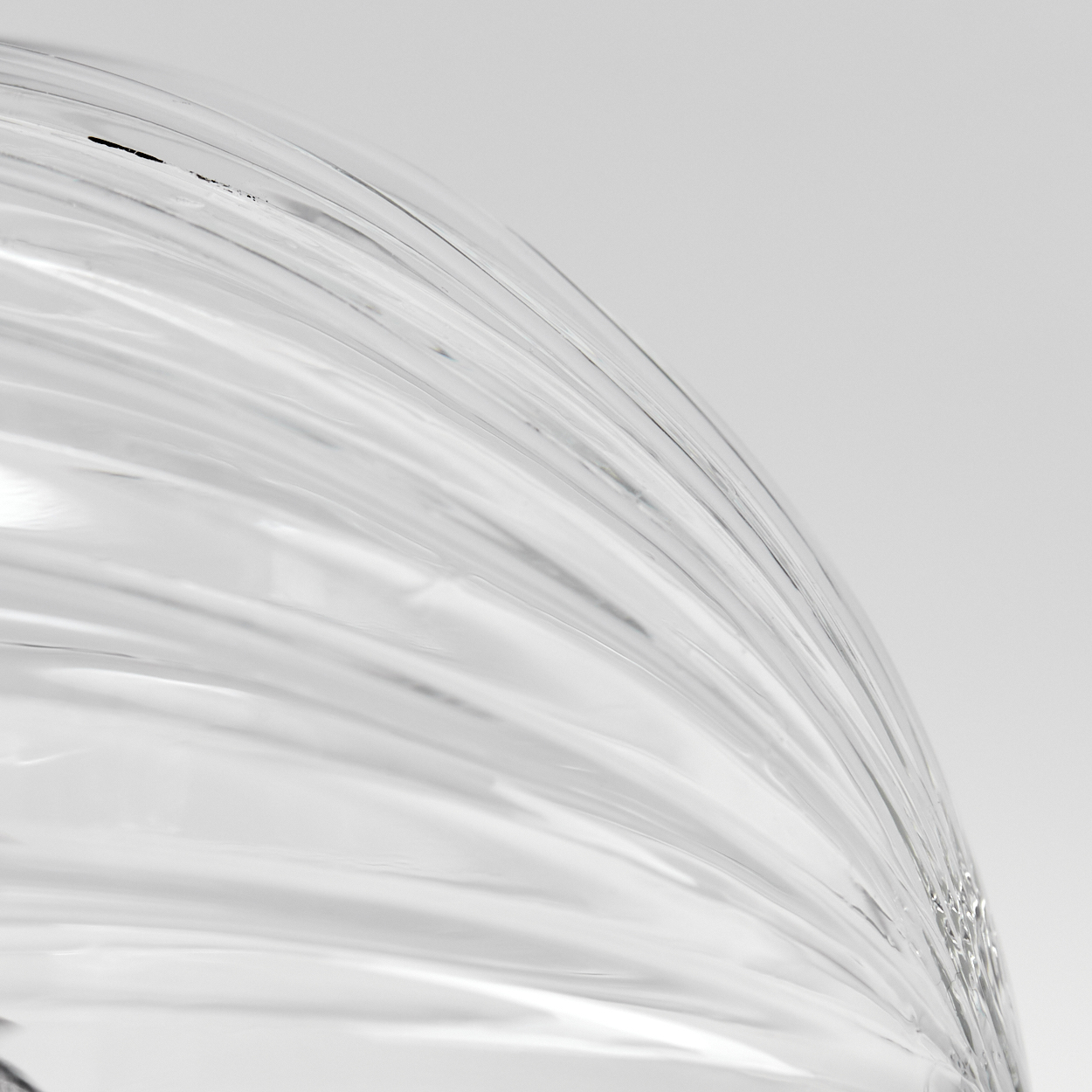 Abstraktes Bild von gebogenem, transparentem Glas mit Lichtreflexen. Der Hintergrund ist ein Gradient von Weiß zu Hellgrau.