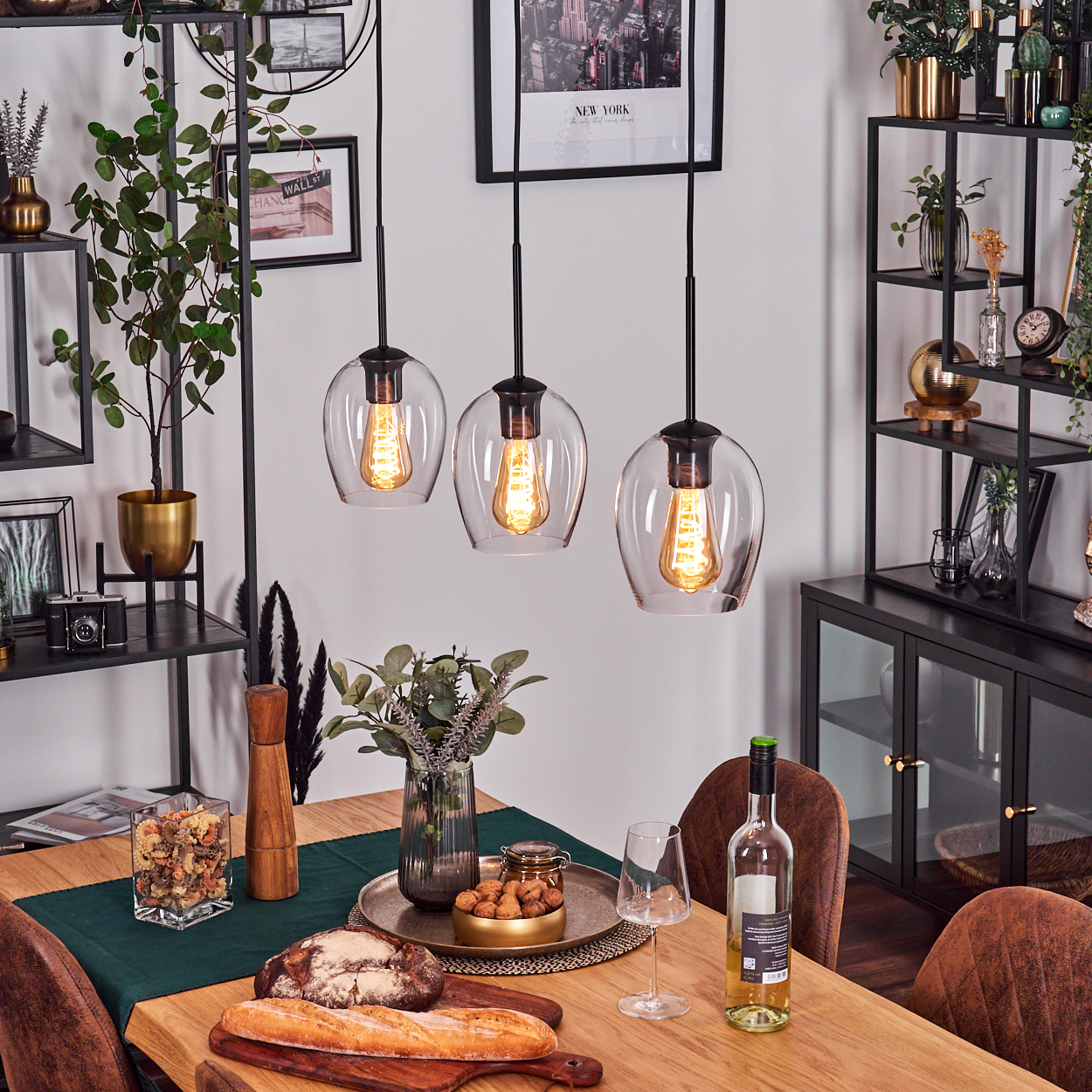 Esszimmer-Szene mit gedecktem Tisch. Drei Hängelampen beleuchten den Tisch mit Brot und Wein.