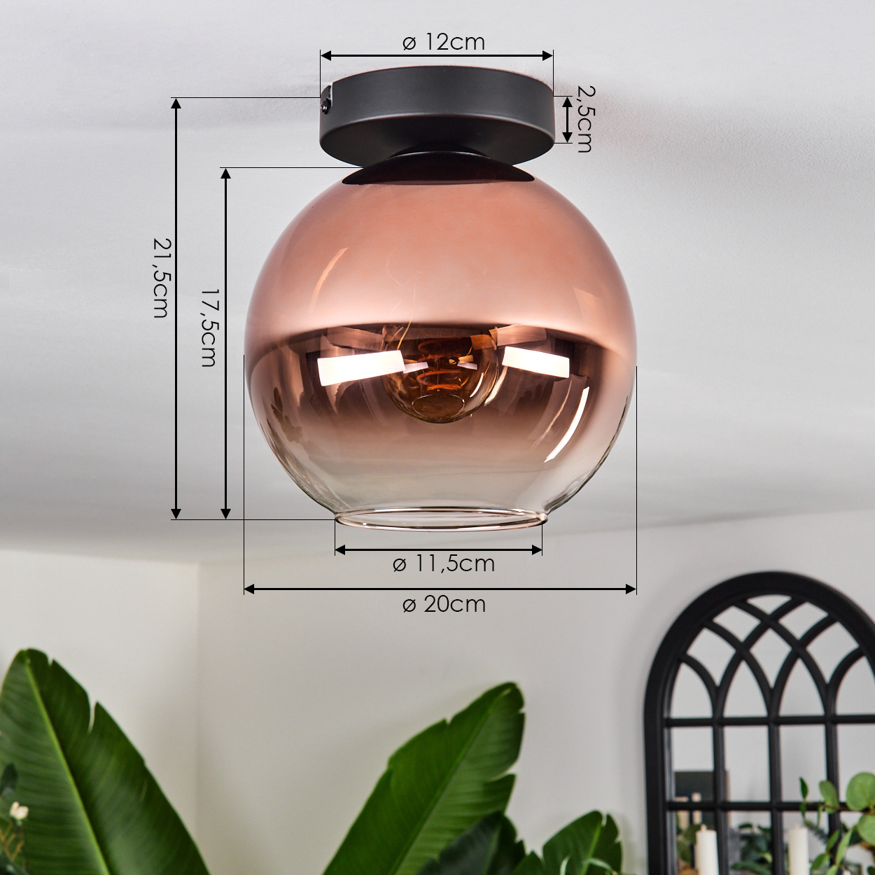Eine moderne Deckenlampe mit kupferfarbenem Glasschirm. Die Abmessungen werden mit schwarzen Linien und Text angezeigt. Grüne Pflanzen im Vordergrund.