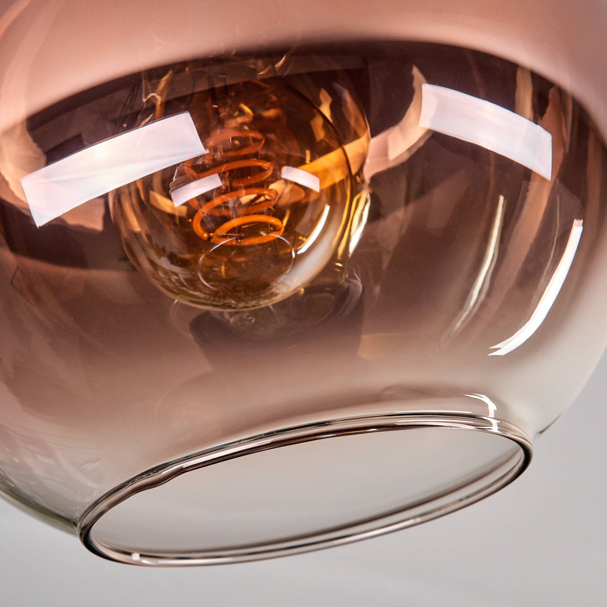 Nahaufnahme einer Glasleuchte mit einer Glühbirne. Das Glas ist rauchfarben, die Glühbirne hat einen Spiralglühfaden.