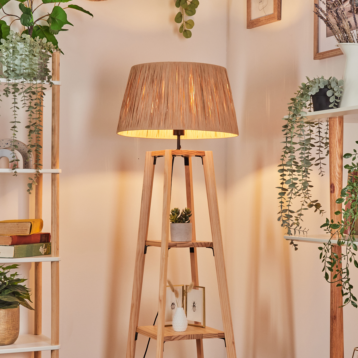 Eine Stehlampe aus Holz mit gewebtem Schirm steht in einem gemütlichen Raum. Regale mit Pflanzen und Büchern sind auf beiden Seiten.
