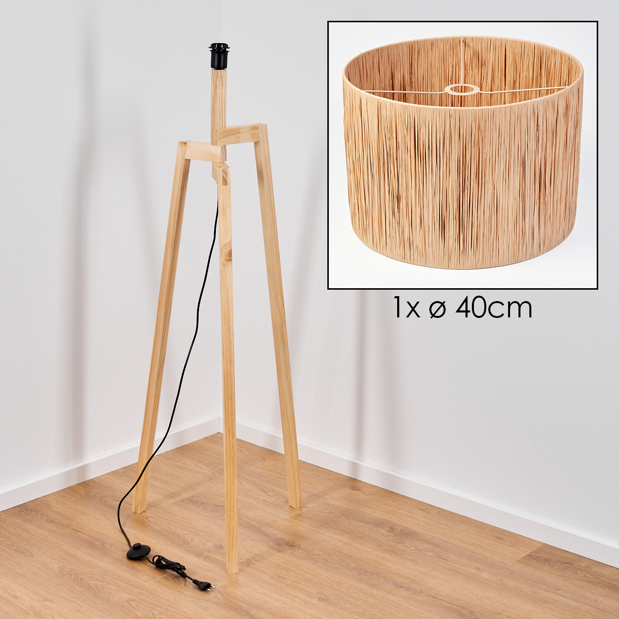 Holz-Dreibein-Lampe mit Lampenschirm in einer Ecke. Der Lampenschirm ist rund, mit einem Durchmesser von 40 cm. Ein schwarzes Netzkabel liegt auf dem Boden.