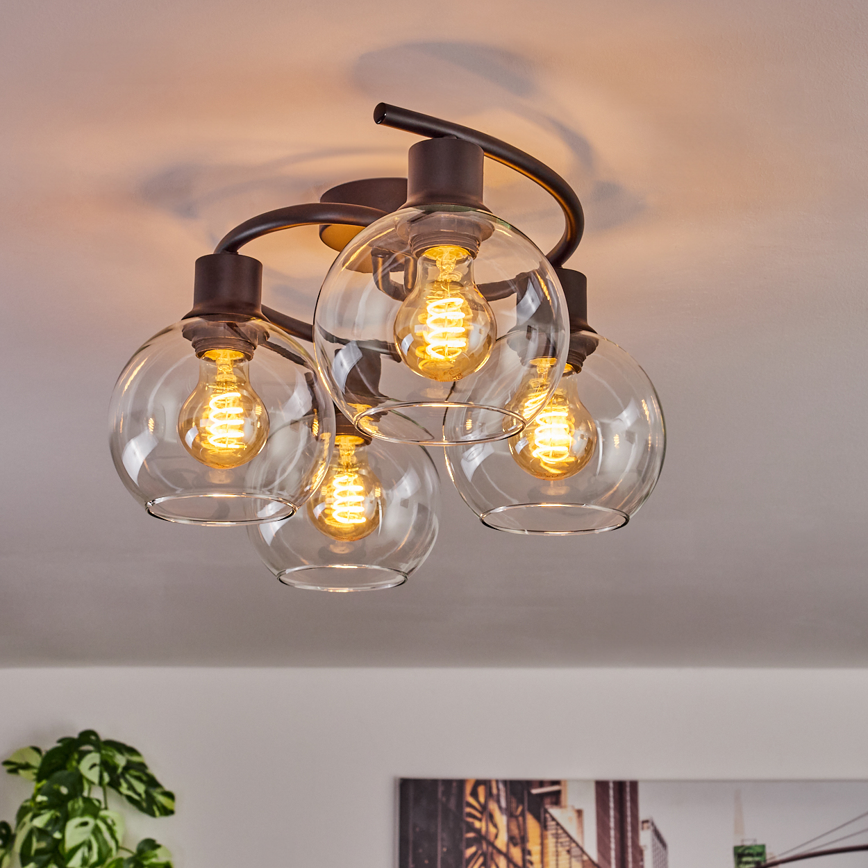 Eine moderne Deckenleuchte mit fünf Glaskugeln, jede mit einer Edison-Glühbirne. Die Leuchte hat dunkle Metallarme.