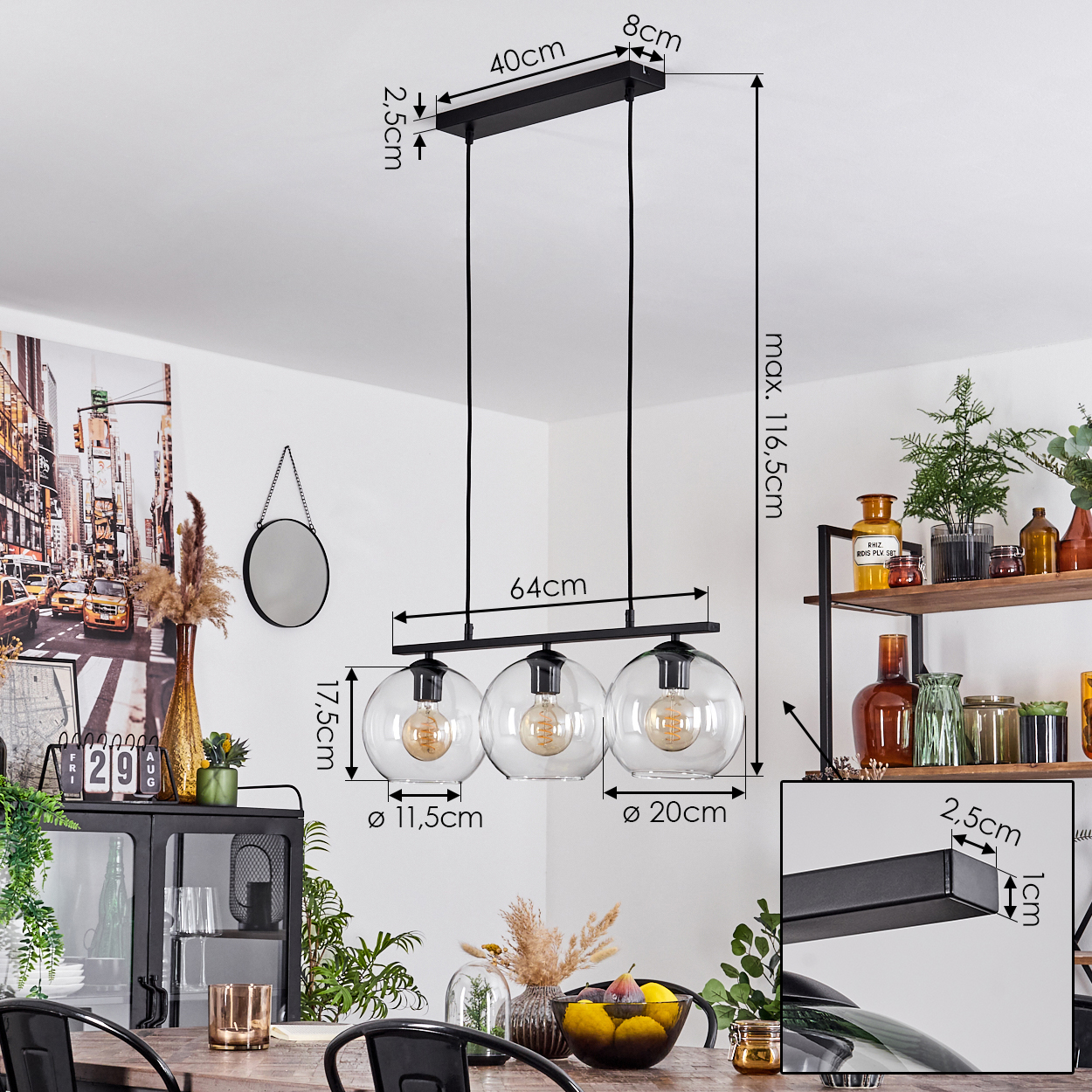 Eine moderne schwarze Pendelleuchte mit drei Glaskugeln hängt über einem Holztisch. Abmessungen sind beschriftet. Der Hintergrund zeigt eine Wand mit Dekor.