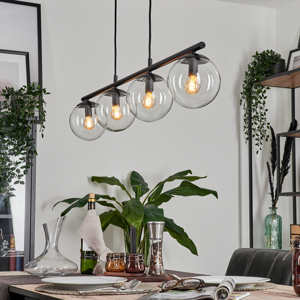 Esszimmer mit gedecktem Tisch. Eine Hängeleuchte mit vier Glaskugeln beleuchtet die Szene.