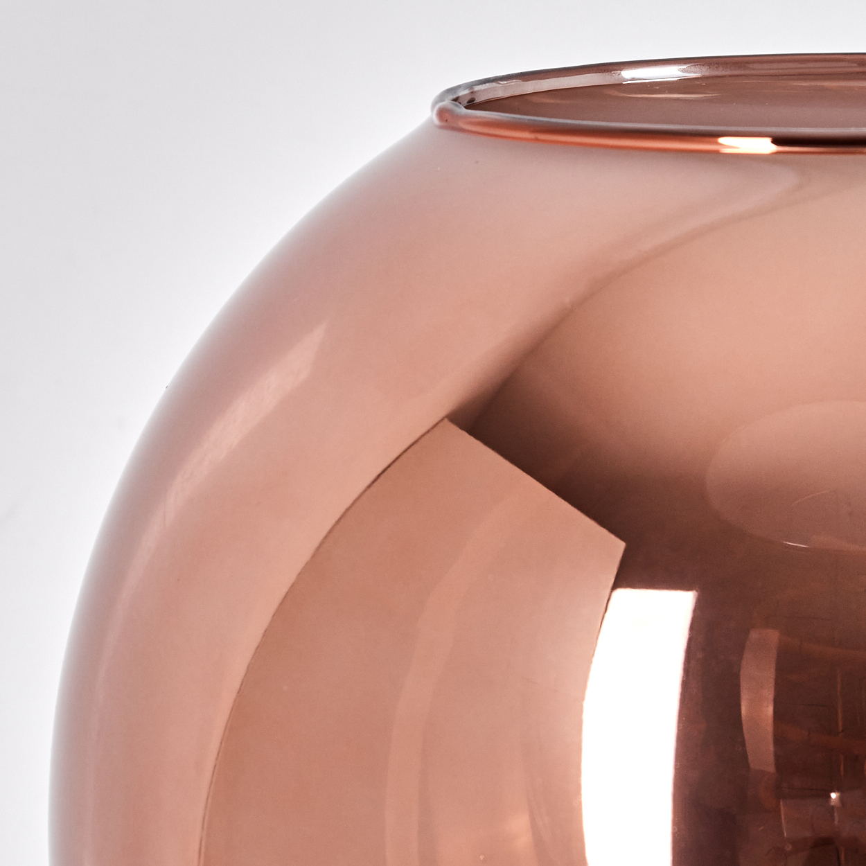 Nahaufnahme eines roségoldenen Objekts mit gewölbten Oberflächen und reflektierendem Finish. Der Hintergrund ist weiß.