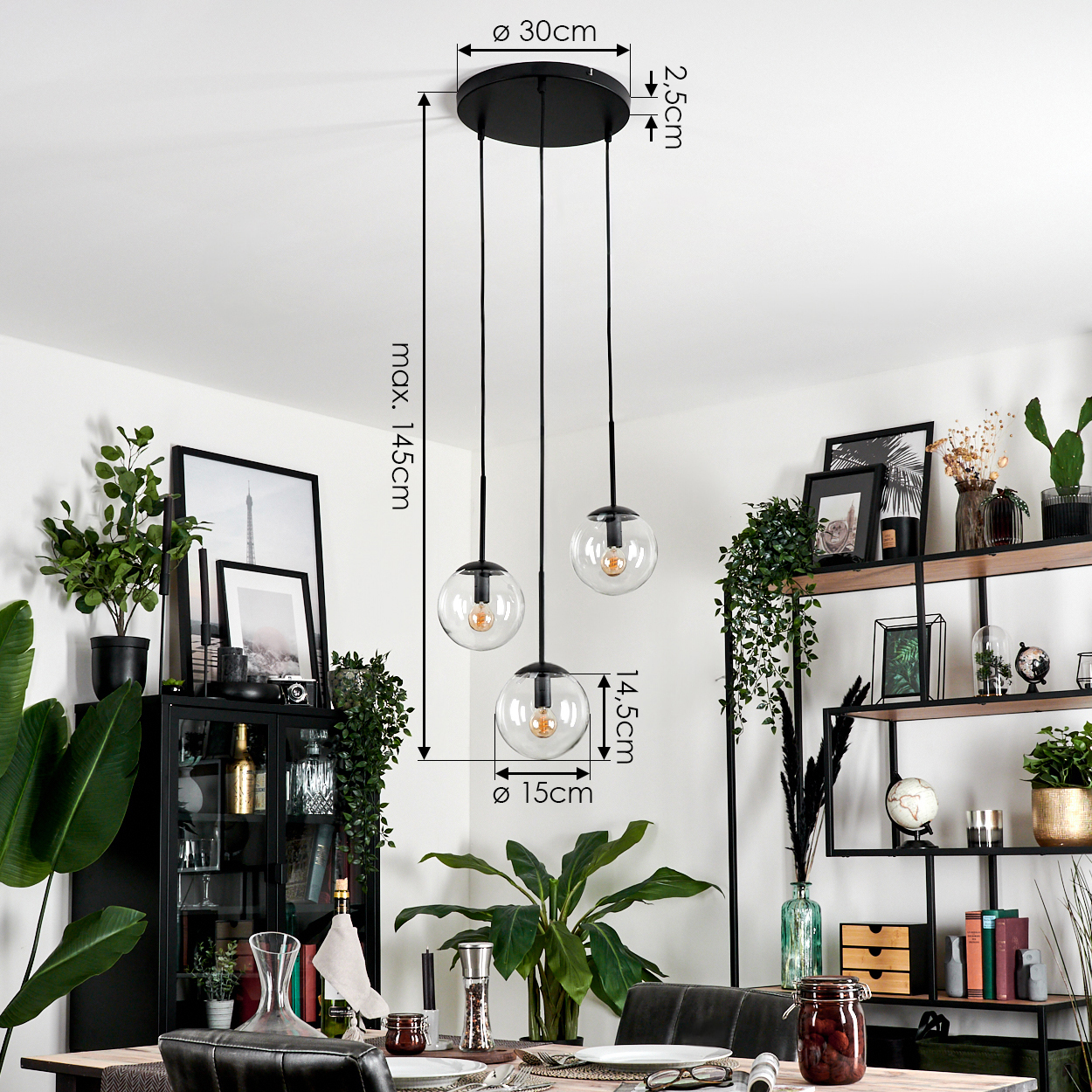 Ein modernes Esszimmer mit einem schwarzen Kronleuchter. Drei kugelförmige Lichter hängen über einem gedeckten Tisch. Pflanzen und Dekor sind sichtbar.