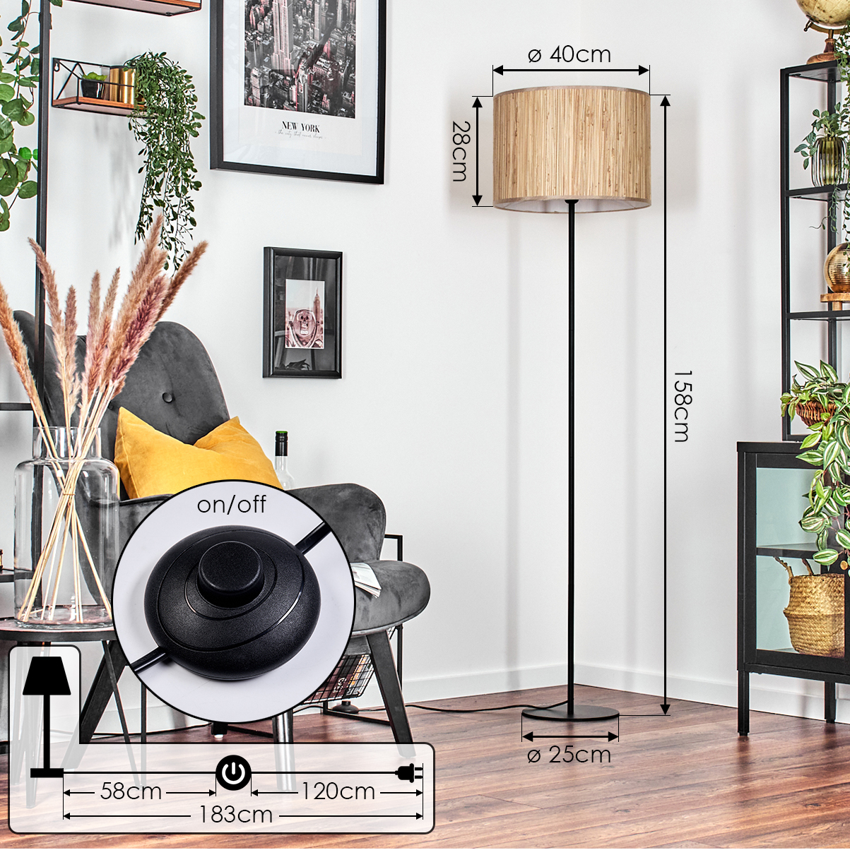 Eine Stehlampe mit beigem Schirm steht in einem Raum. Im Hintergrund ein Stuhl, Bilder und Pflanzen. Die Lampe hat einen Fußschalter.