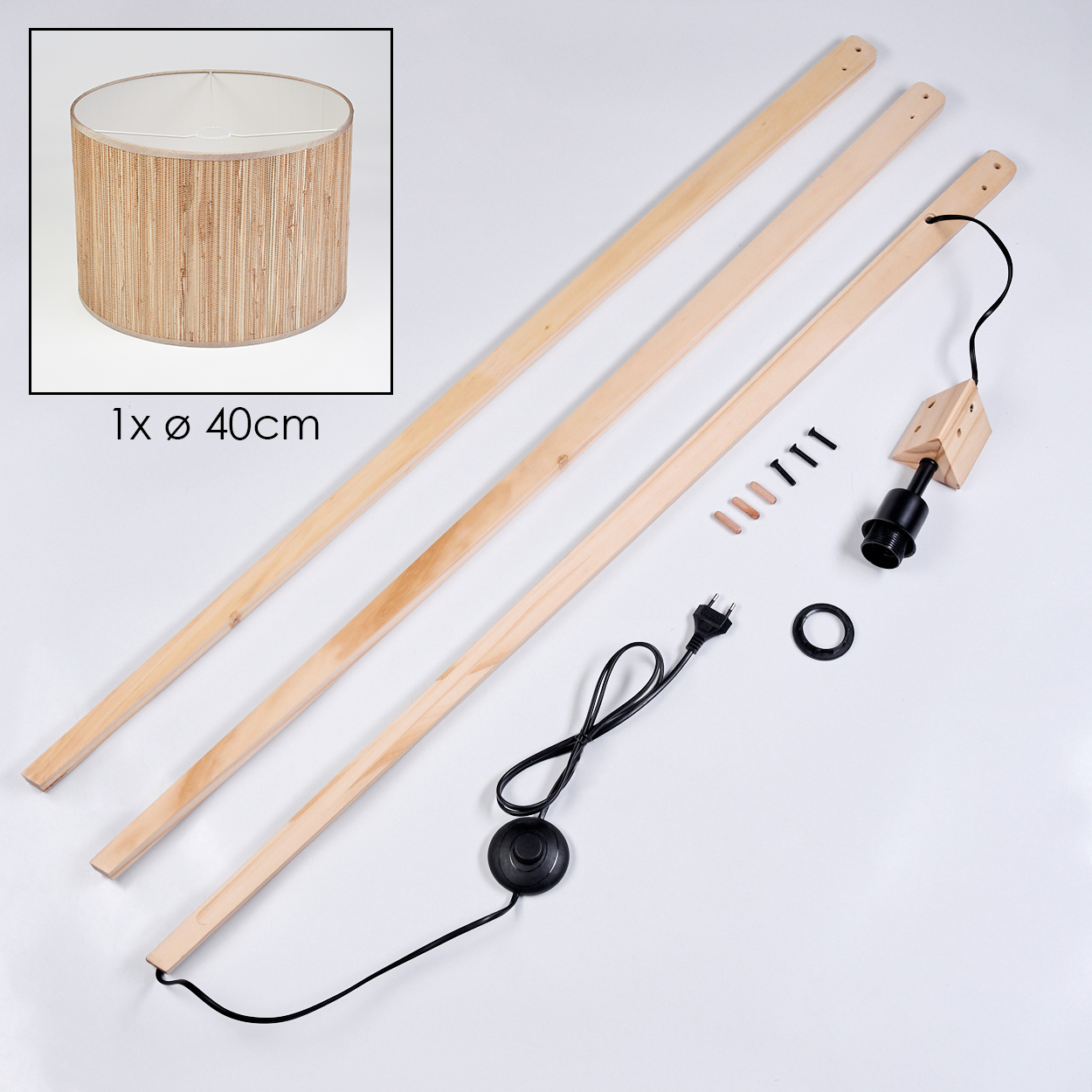 Ein zerlegter Lampenbausatz auf Weiß. Enthält Lampenschirm, Holzstangen, Schrauben, Lampenfassung und ein Netzkabel mit Fußschalter.
