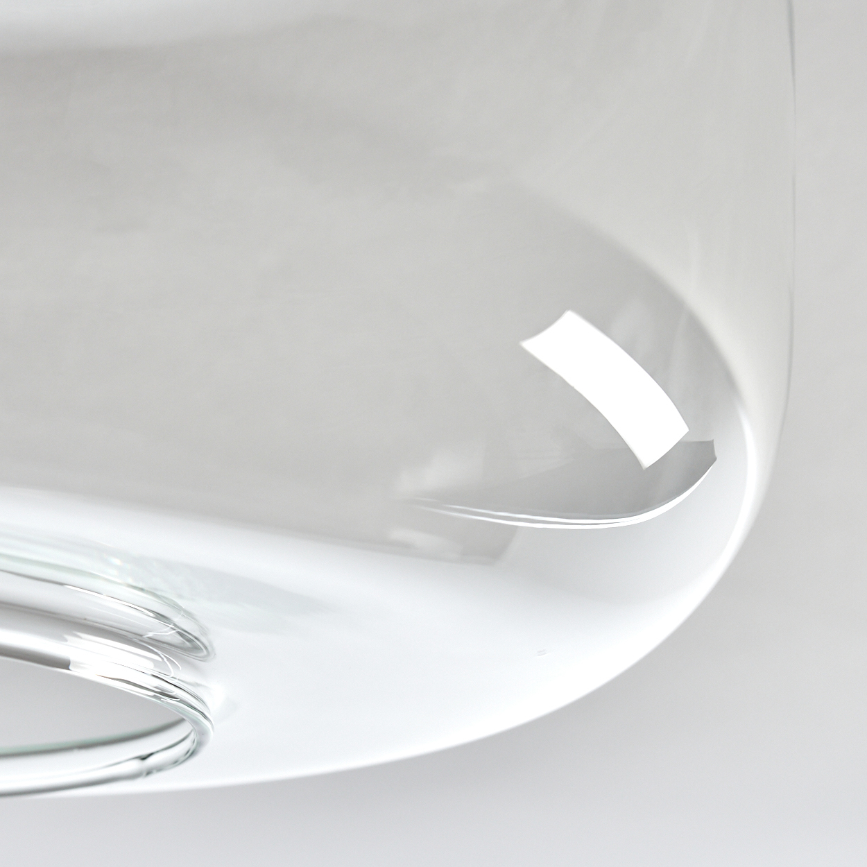 Nahaufnahme eines klaren Glasobjekts. Es hat eine abgerundete Form mit reflektierender Oberfläche. Der Hintergrund ist ein weicher weißer Farbverlauf.