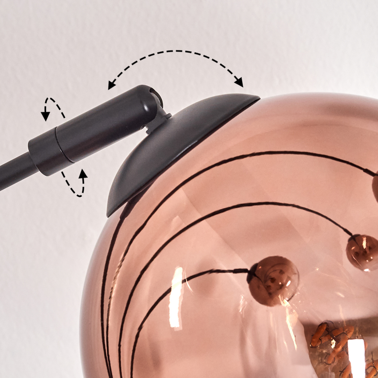 Nahaufnahme einer Lampe. Ein schwarzer Arm verbindet sich mit einer kupferfarbenen Kugel mit schwarzen Linien. Pfeile zeigen die Bewegung an.