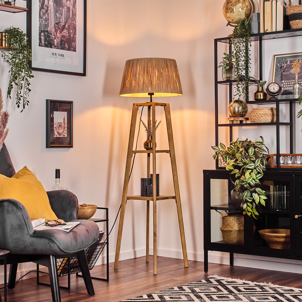 Ein Raum mit einer Holzlampe, einem grauen Stuhl mit gelbem Kissen und einem schwarzen Bücherregal mit verschiedenen Dekorationen.