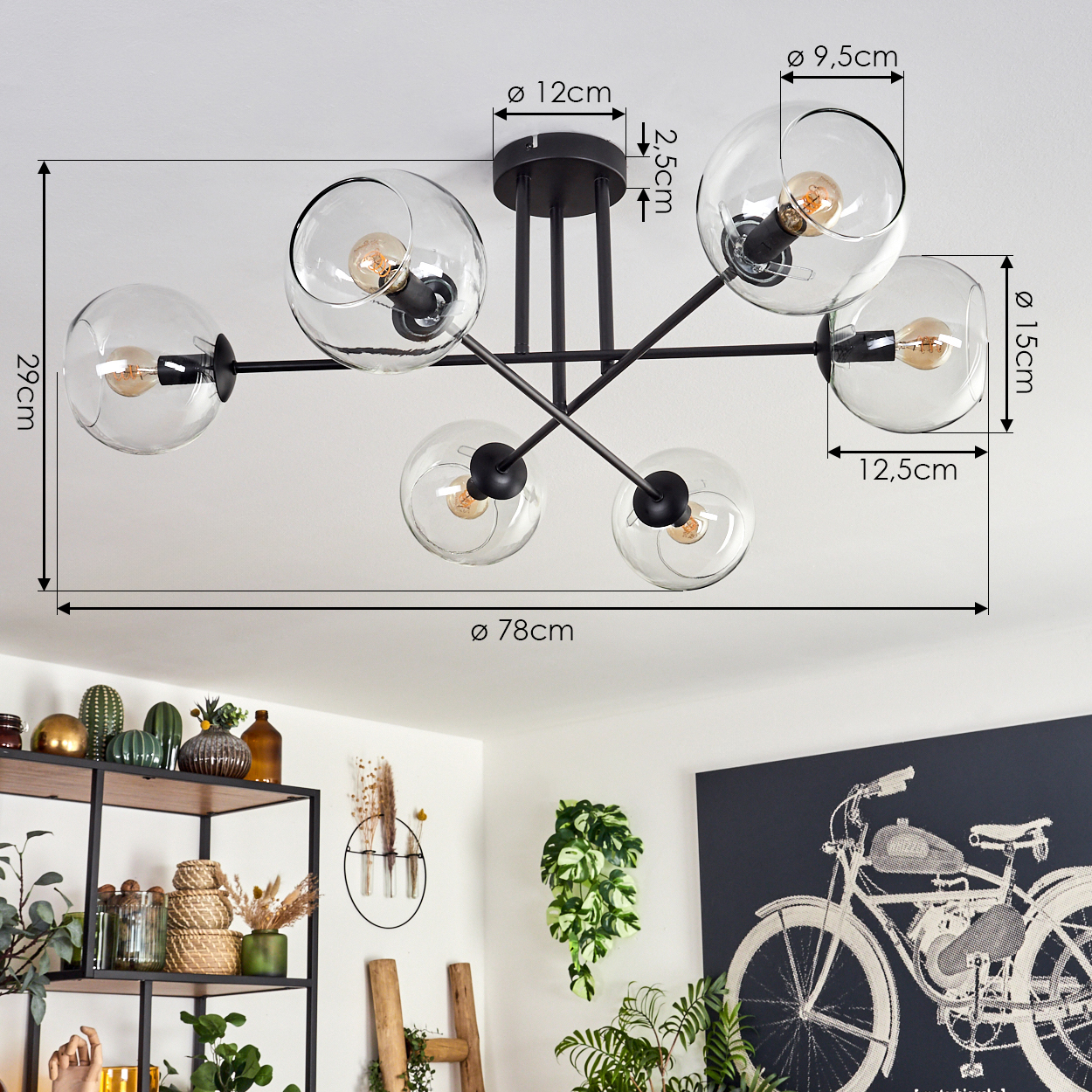 Eine moderne Deckenlampe mit sechs Glaskugel-Schirmen. Der schwarze Rahmen kontrastiert mit der weißen Decke. Der Raum hat Dekoration und Pflanzen.