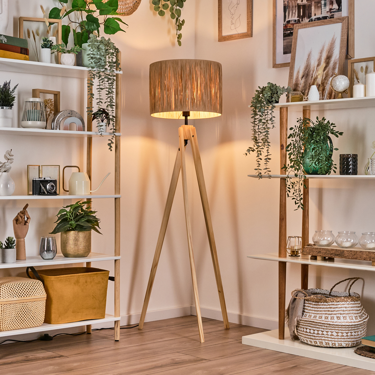 Raumecke mit Holzboden, Regalen mit Pflanzen und Dekoration. In der Mitte steht eine Lampe mit braunem Lampenschirm.